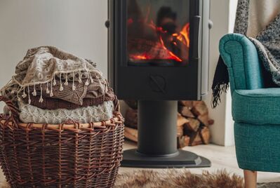 A blanket basket and an armchair in front of a fire