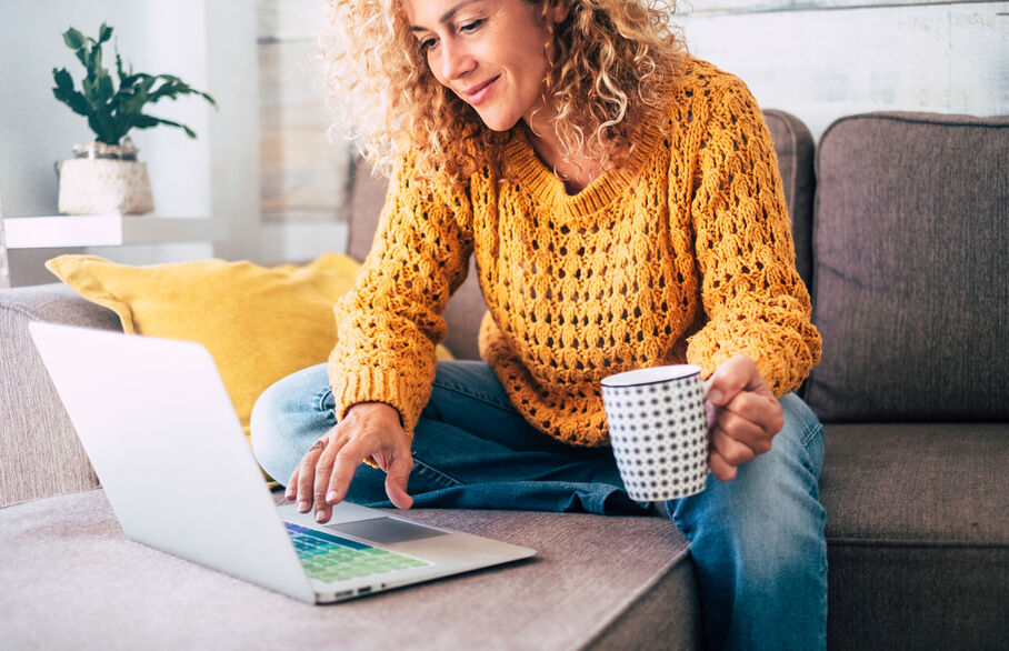 Woman in yellow jumper sitting in front of a laptop