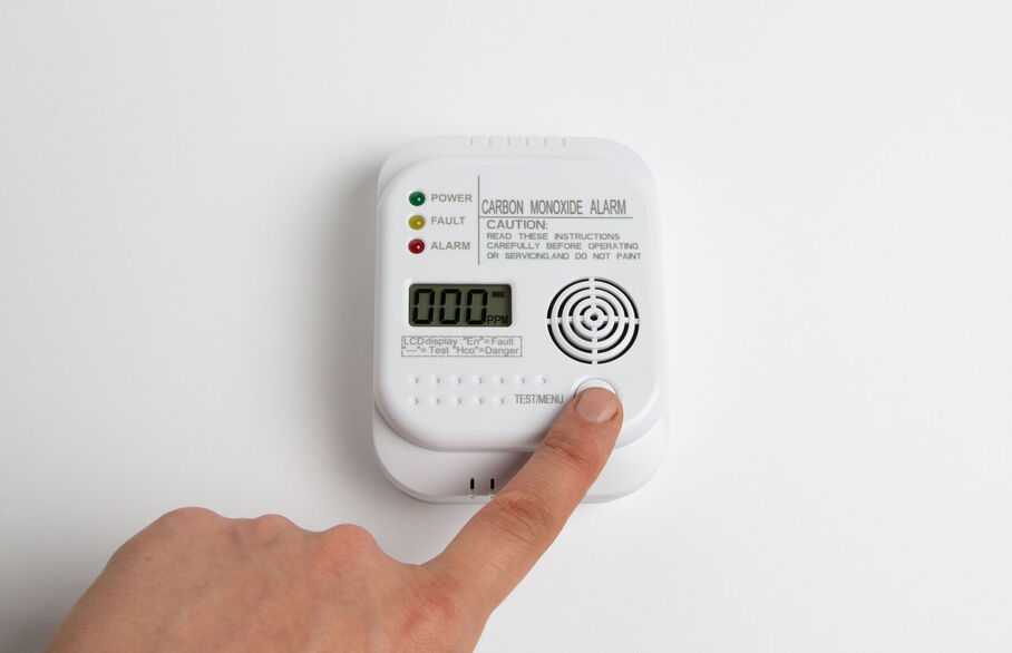 Someone pushing a button on a carbon monoxide detector