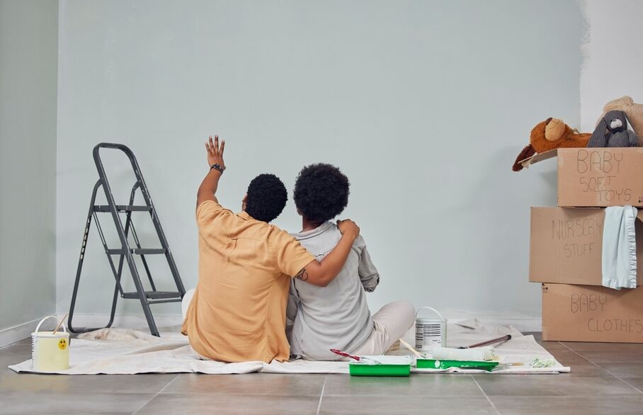 Two people sitting on the floor looking at a newly painted wall