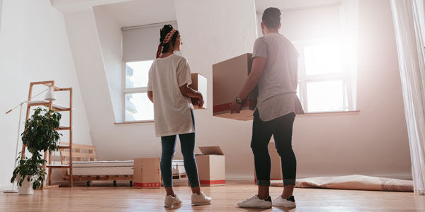 Full length rear view shot of young couple carrying cardboard box at new home. 