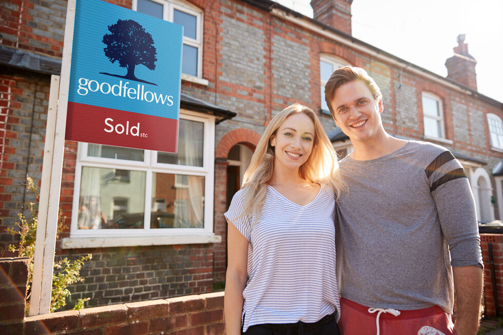 Happy couple stood next to Goodfellows sold board