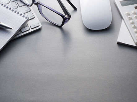 Calculator, glasses and notepad on grey desk, 